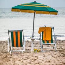 Sedie a sdraio e ombrellone su una spiaggia con vista sul mare.