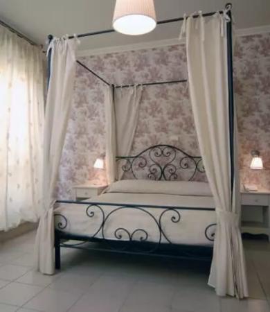 Camera da letto con letto a baldacchino e carta da parati floreale.