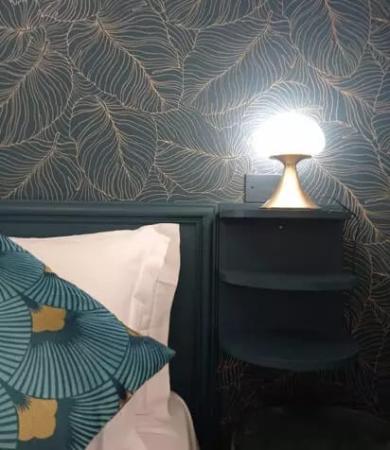 Camera da letto elegante con lampada moderna e carta da parati a foglie.