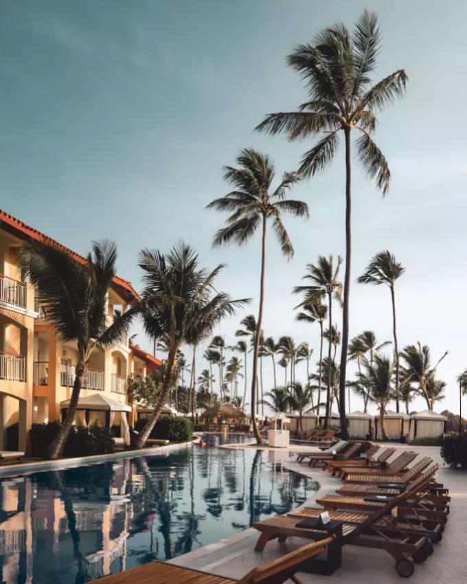 Piscina con lettini e palme in un resort tropicale al tramonto.