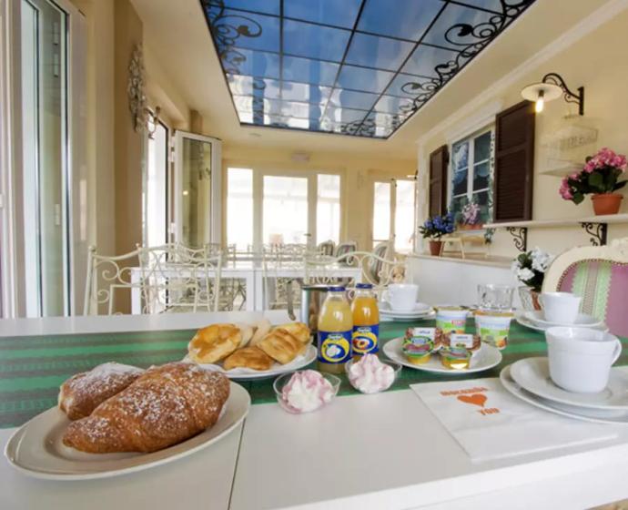 Colazione italiana con cornetti, succo e yogurt in una sala luminosa ed elegante.